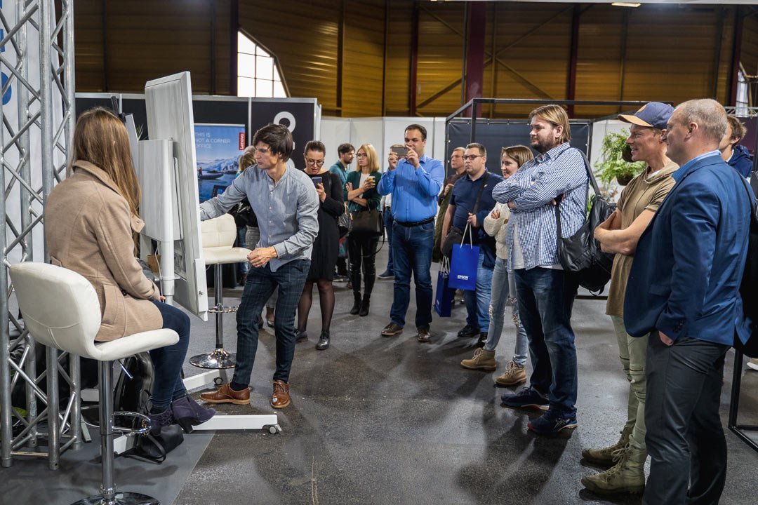 Karikatūrists zīmē uz Samsung Flip tāfeles un apkārt esošie cilvēki to ar interesi vēro