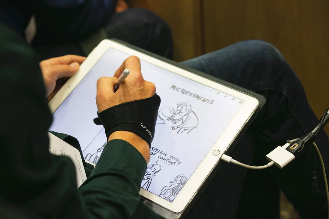Karikatūrists zīmē konferencē uz iPad Pro planšetes