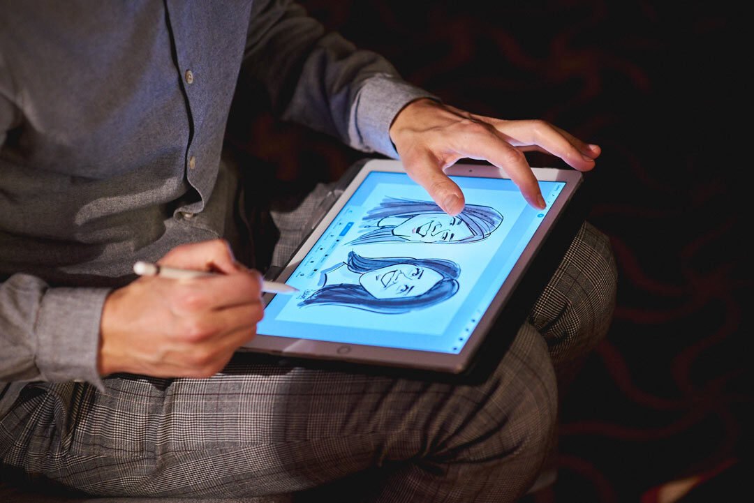 Karikatūrists ar Apple zīmuli zīmē digitālas karikatūras uz planšetes